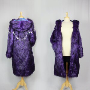 May include: Purple faux fur coat with a hood and a chain of silver charms around the neckline. The coat is on a wooden mannequin.