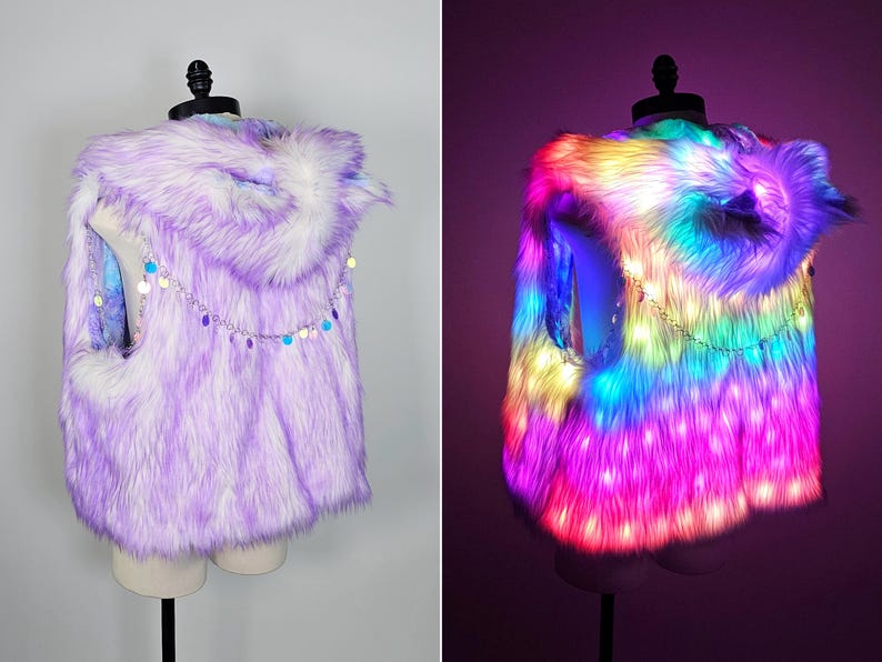 May include: A sleeveless faux fur vest with a hood, featuring a light purple and white color palette. A silver-toned chain with small, circular, iridescent sequins is draped across the back. The vest is equipped with integrated LED lights.