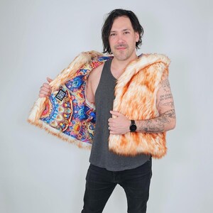 May include: A sleeveless vest made of orange and white faux fur. The interior lining features a vibrant, multicolored psychedelic mandala pattern with intricate geometric shapes and circular designs in shades of blue, red, yellow, and purple.