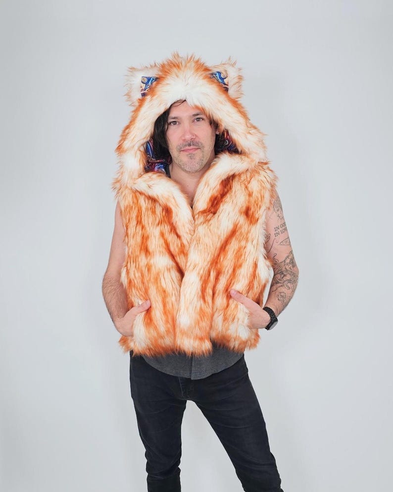 May include: A sleeveless vest made of orange and white faux fur featuring an attached hood with pointed ears. The interior lining of the hood displays a colorful, intricate paisley pattern in shades of blue, red, and gold. The vest has two front pockets.