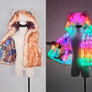 May include: A sleeveless faux fur vest with an attached hood featuring animal ears. The exterior is orange and white, while the interior lining displays a colorful, intricate mandala pattern. The vest includes integrated LED lights.