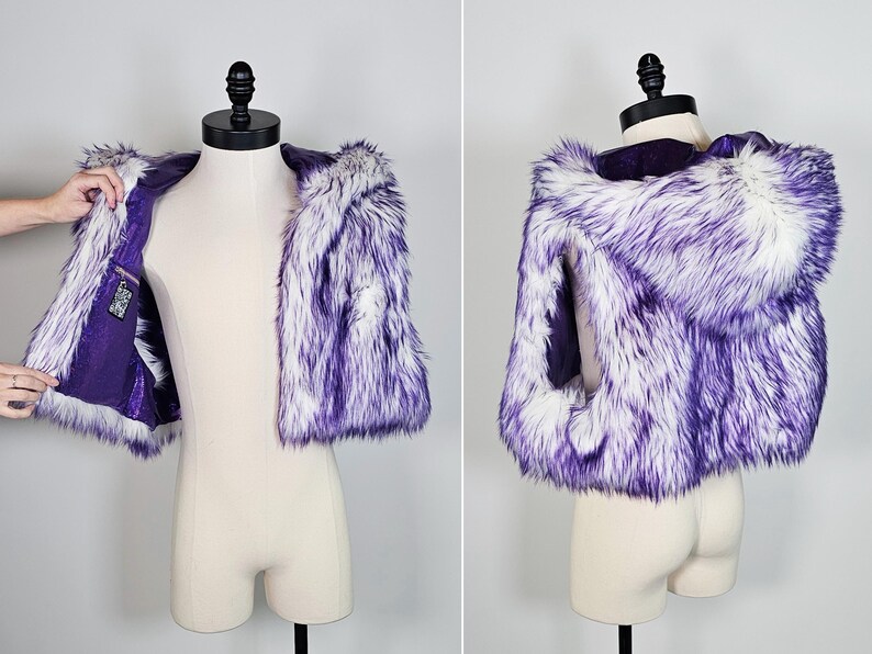 May include: A sleeveless faux fur vest featuring a hooded design with long, shaggy white and purple-tipped fibers. The interior is lined with a solid purple fabric and includes a small rectangular pocket on the inner left side with a patterned label.