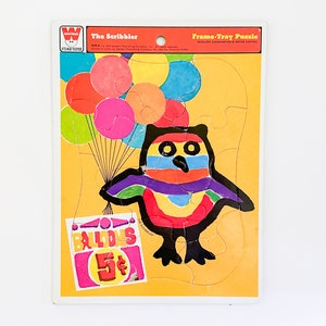 May include: A vintage frame-tray puzzle featuring a colorful owl holding a sign that reads "Balloons 5¢". The owl is surrounded by colorful balloons. The puzzle is made by The Scribbler.