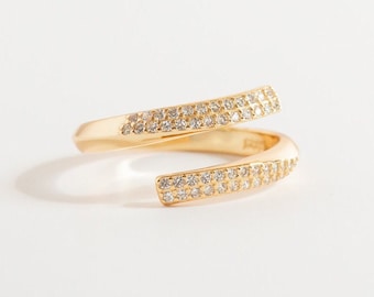 May include: A gold ring with a double band design, both bands are set with small clear stones.