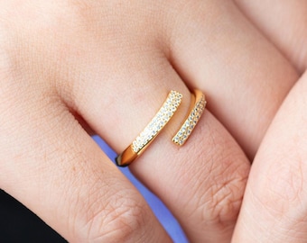 May include: A gold ring with a double band design, both bands are encrusted with small clear stones.