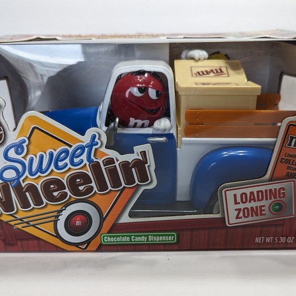 Limited Edition "Sweet Wheelin" M&M candy dispenser, features Red's garage and loading zone, with blue pickup. Yellow is the mechanic. NIB