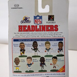 May include: A colorful cardboard backer for a set of NFL Headliners collectible figurines. The backer features a red, white, and blue color scheme with the NFL logo and the words "Headliners" in large, bold letters. The backer also features images of eight different NFL players, including Jerome Bettis, Keyshawn Johnson, Dan Marino, Cris Carter, Greg Lloyd, Mark Brunell, Michael Irvin, and Gus Frerotte.