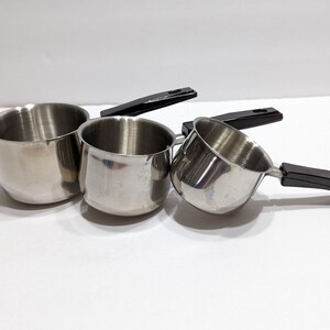 May include: Three stainless steel saucepans with black plastic handles. The saucepans are nested together, with the smallest saucepan on top.