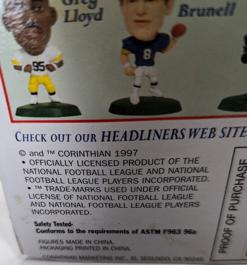 May include: A close-up of a product box featuring two NFL football player figurines. The box is green and white with the text "CHECK OUT OUR HEADLINERS WEB SITE" and "PROOF OF PURCHASE". The text "and TM CORINTHIAN 1997" is also visible on the box.