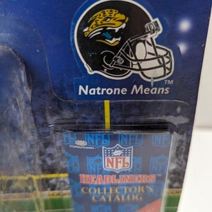 May include: A blue and white NFL Headliners Collector's Catalog card with a black and yellow Jacksonville Jaguars helmet sticker featuring a jaguar. The sticker reads "Natrone Means" and "TM".