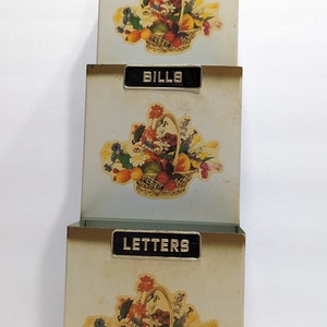 Vintage mail sorter, wall mount, with flower and fruit basket motif.  Missing misc sticker, shows some signs from use.  19"high x 5" wide.