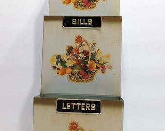 Vintage mail sorter, wall mount, with flower and fruit basket motif.  Missing misc sticker, shows some signs from use.  19"high x 5" wide.