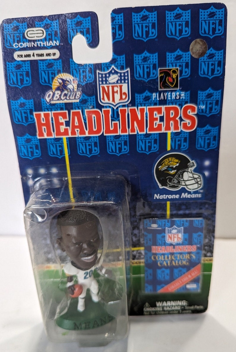 May include: A plastic figure of NFL player Natrone Means wearing a Jacksonville Jaguars uniform. The figure is holding a football and is standing on a green base. The figure is packaged in a clear plastic blister pack with a blue and white cardboard backing. The backing features the NFL logo and the words "Headliners" and "Players".
