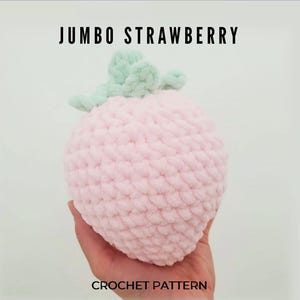 May include: A jumbo, light pink crocheted strawberry with a light green stem and leaves. The text "JUMBO STRAWBERRY" is above the strawberry, and "CROCHET PATTERN" is below.