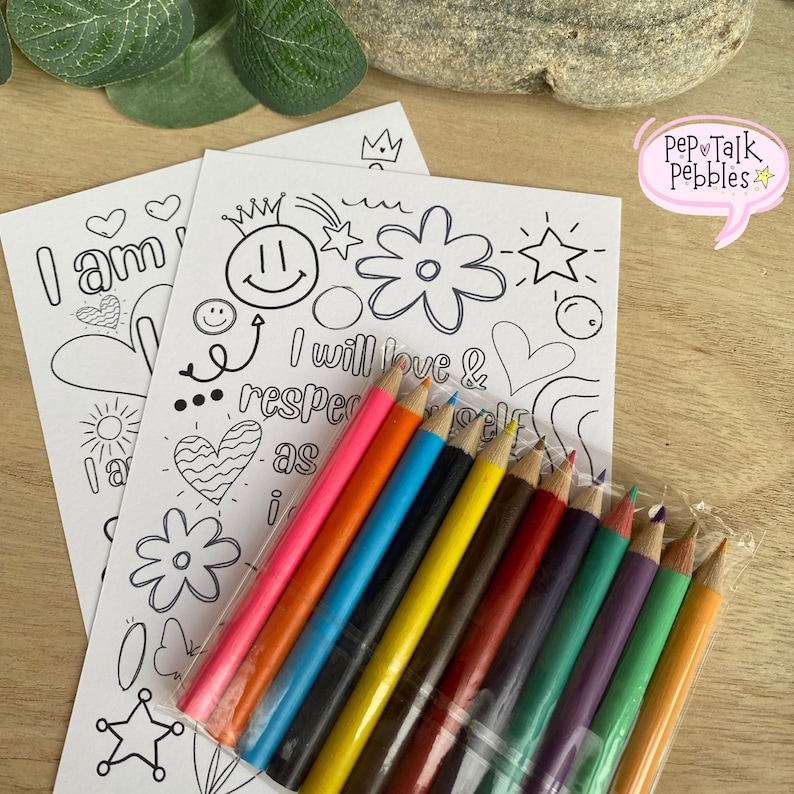 May include: Two black and white coloring pages with positive affirmations and doodles. The pages are next to a pack of ten colored pencils in a clear plastic bag.