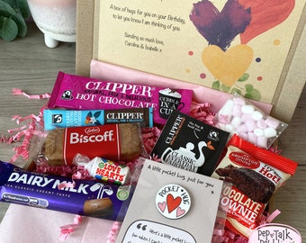 May include: A pink and brown gift box filled with various treats, including chocolate, biscuits, hot chocolate, tea, and marshmallows. The box includes a card with the text "A box of hugs for you on your Birthday, to let you know I am thinking of you. Sending so much love, Caroline & Isabelle x".