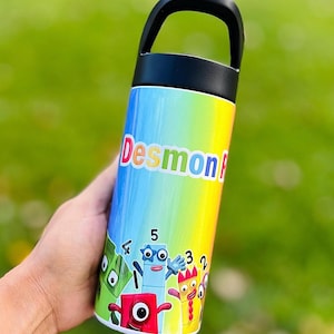 May include: A colorful water bottle with a black handle. The bottle features the name "Desmon" in red and white letters. The bottle has a rainbow gradient background and cartoon number characters.