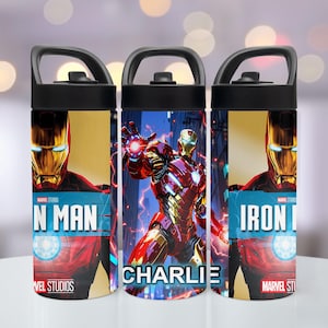 May include: Three cylindrical water bottles with black lids and handles, featuring Iron Man graphics. The design includes the text 'IRON MAN', 'MARVEL STUDIOS', and the name 'CHARLIE' in white lettering against a red, gold, and blue background.