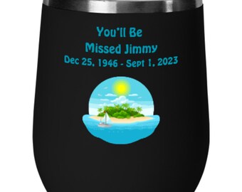 May include: Black stainless steel wine tumbler with a blue and green island scene and the text "You'll Be Missed Jimmy Dec 25, 1946 - Sept 1, 2023"