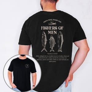 Op de afbeelding: Zwart t-shirt met de tekst "JESUS WILL MAKE YOU FISHERS OF MEN" en drie visillustraties op de achterkant. De tekst "Matthew 4:18:19" en een bijbelvers staan ook op het shirt.