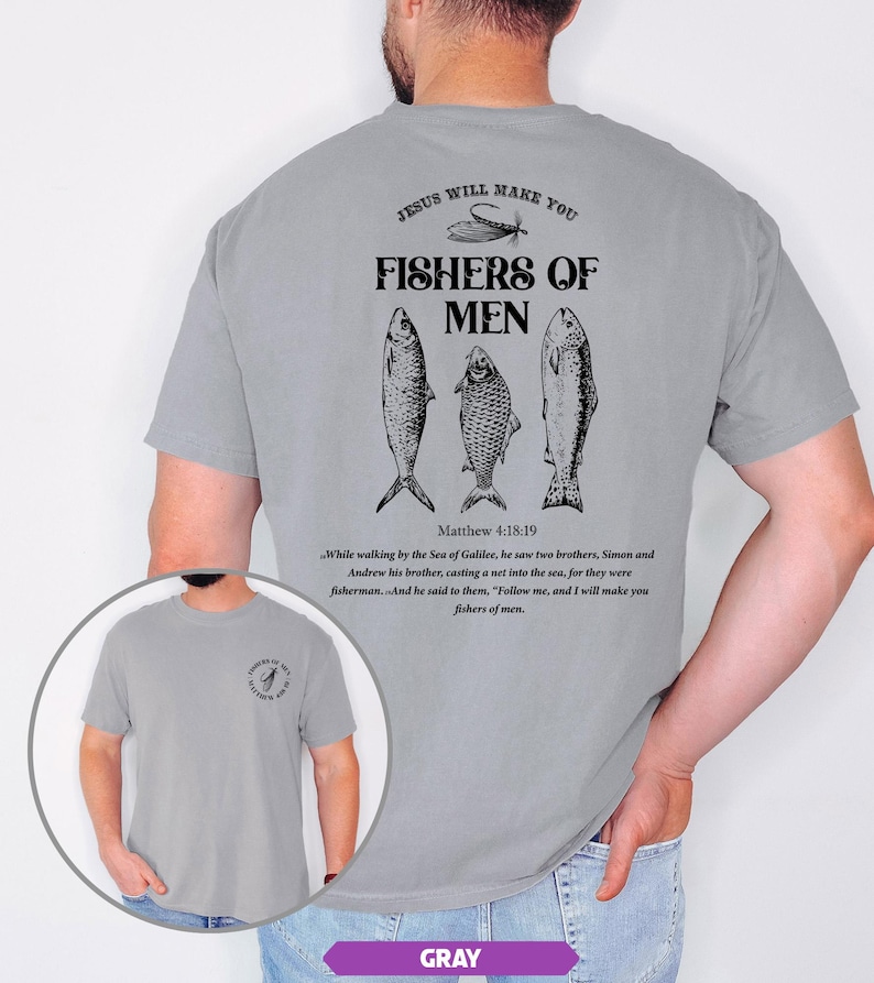 Op de afbeelding: Grijze t-shirt met de tekst "JESUS WILL MAKE YOU FISHERS OF MEN" en drie visillustraties. De achterkant van de shirt bevat ook een bijbelvers uit Matthe&uuml;s 4:18-19. De shirt is een casual, comfortabele stijl.