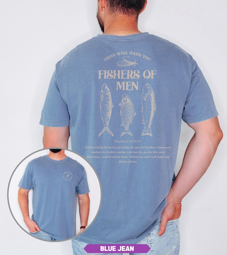 Op de afbeelding: Blauw spijkerstof T-shirt met korte mouwen met een afbeelding op de achterkant met de tekst "FISHERS OF MEN" met drie visillustraties. De tekst "JESUS WILL MAKE YOU" staat boven de afbeelding. Een kleinere afbeelding staat op de voorkant.