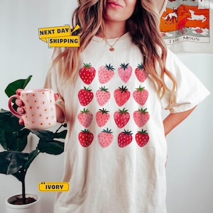 A soft vintage-style t-shirt featuring a cute hand-drawn strawberry graphic. Cottagecore-inspired, comfy and colorful—ideal for warm summer days and garden lovers.