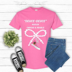 Peut inclure: T-shirt rose avec le texte "Deuce-Deuce" Rockin' Chucks & Pearls. Un nœud de perles blanches avec une chaussure rose et blanche est au centre du t-shirt.
