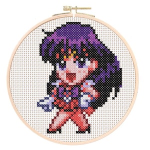 May include: Cross-stitch embroidery hoop featuring a pixelated anime character with purple hair, a red and white outfit, and a yellow star on her forehead.