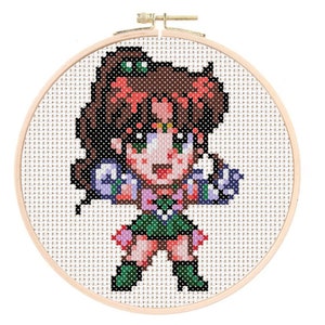 May include: Cross-stitch pattern of a cartoon character with brown hair, green eyes, and a pink and green outfit. The character is holding a green object in each hand.