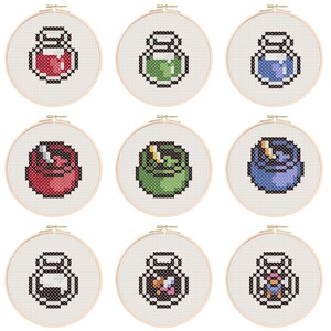 Peut inclure: Neuf cerceaux à broder avec des flacons de potion pixelisés de différentes couleurs. Les flacons sont rouge, vert, bleu, rose, vert clair, violet, noir, rose et blanc.