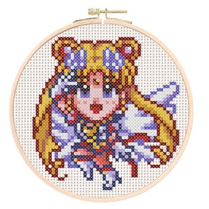 May include: Cross-stitch embroidery hoop featuring a pixelated image of a blonde anime character with a blue and purple dress and a yellow star on her forehead.