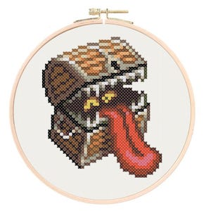 May include: A brown and gold treasure chest with a toothy grin and a red tongue sticking out. The chest is embroidered with a pixelated design.