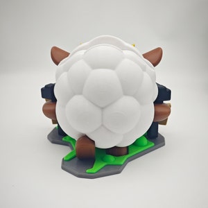 May include: White sheep figurine with brown legs and horns, standing on a green and gray base. The sheep has a soccer ball-like texture.