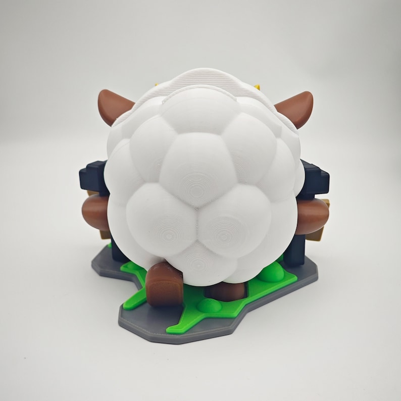 May include: White sheep figurine with brown legs and horns, standing on a green and gray base. The sheep has a soccer ball-like texture.