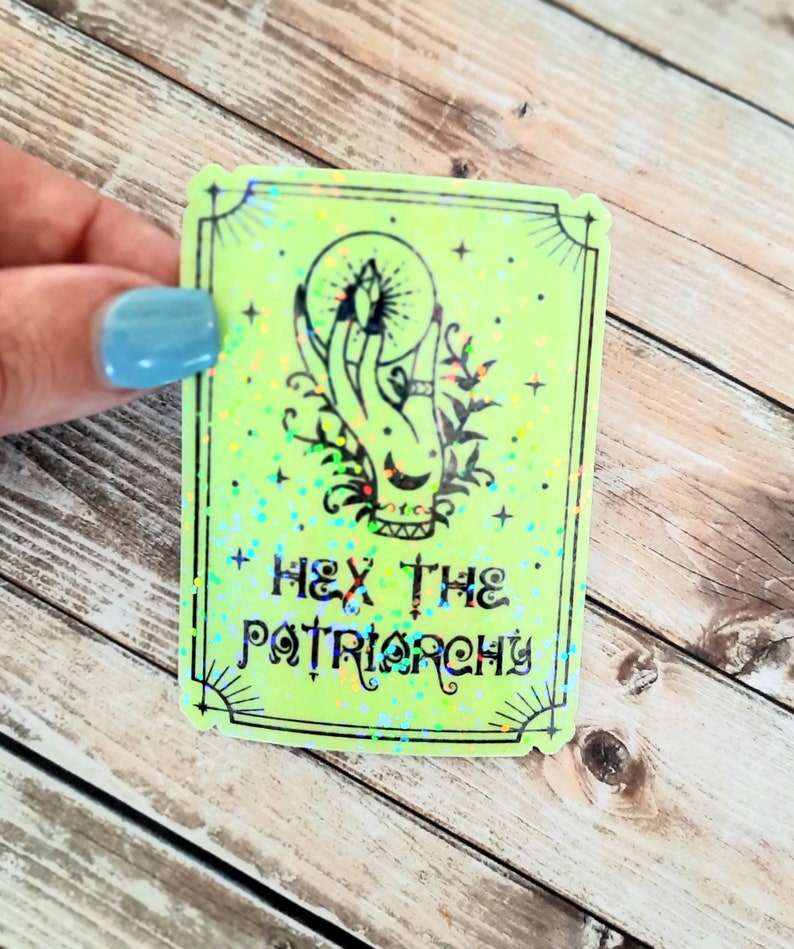 May include: A green holographic sticker with a hand holding a crystal ball and the text "Hex the Patriarchy".