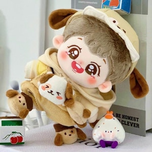 May include: A plush toy in the shape of a child wearing a brown and white hooded jacket with a brown and white hat. The toy is holding a smaller plush toy in the shape of a dog. The toy is standing on a white surface with a small toy in the shape of a rice ball.
