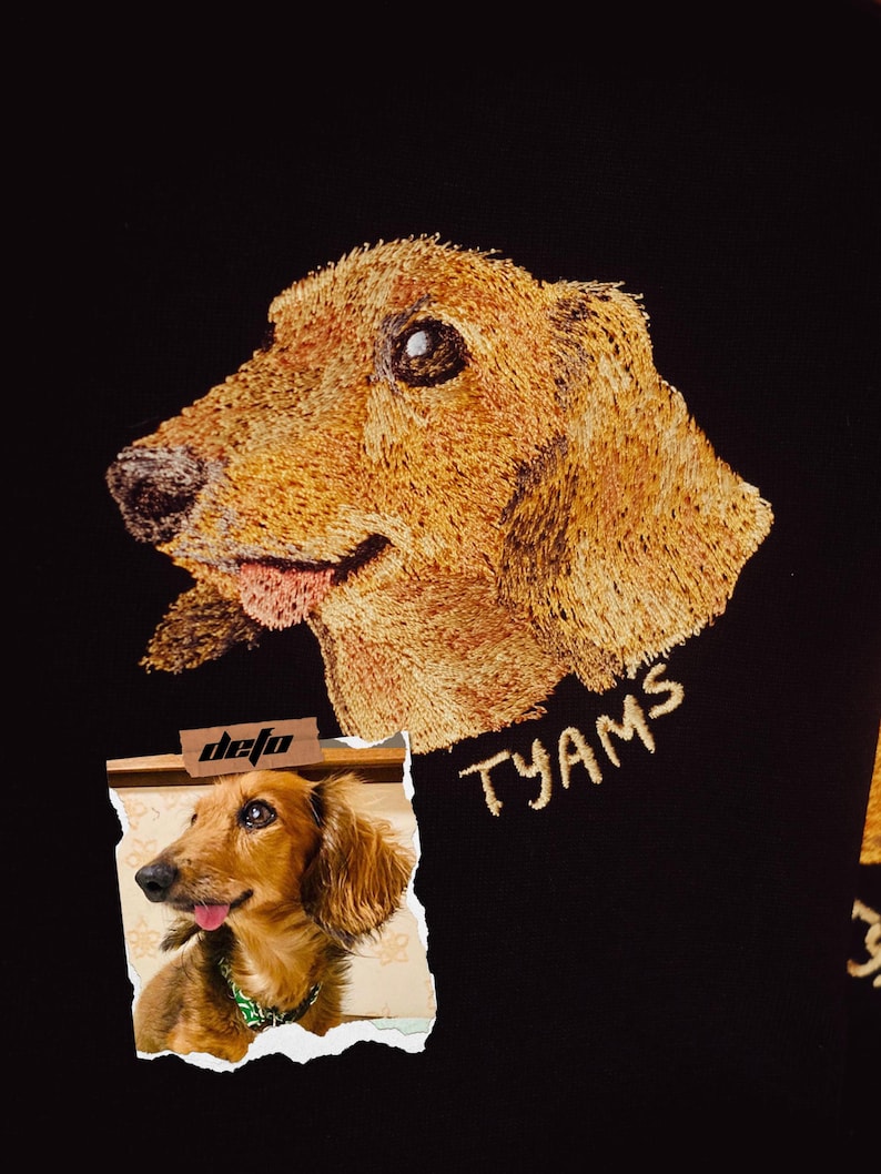 Puede incluir: Imagen bordada de un perro dachshund sobre un fondo de tela negro. El perro es marr&oacute;n y tiene la lengua fuera. El texto "TYAMS" est&aacute; bordado en hilo dorado debajo del perro. Un trozo de papel rasgado con una foto de un perro dachshund y el texto "defo" est&aacute; en la esquina inferior izquierda de la imagen.