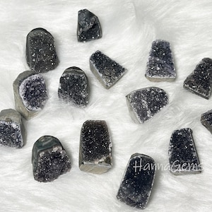 Könnte beinhalten: Eine Sammlung von 12 Amethyst-Geoden in verschiedenen Formen und Größen. Die Geoden sind dunkelviolett und haben eine glitzernde, kristalline Textur.
