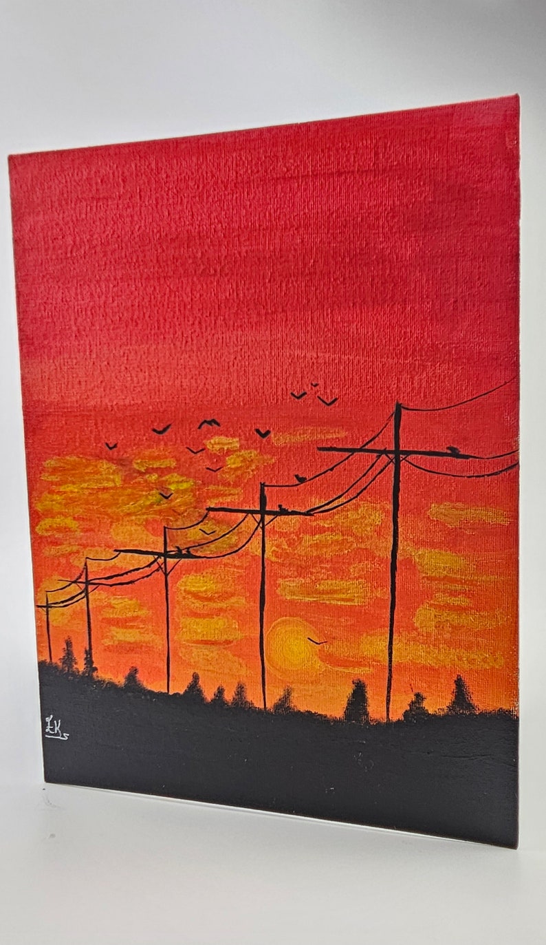 May include: A painting of a sunset with power lines and birds flying in the sky. The sky is a gradient of red, orange, and yellow. The power lines are black and the birds are silhouetted against the sky. The painting is signed "EK" in the bottom left corner.