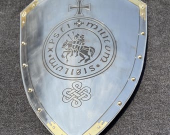 May include: A silver shield with a cross at the top and a circular design in the center. The design features a knight on horseback with the text "XPS. MILITVM. SIGILLVM" around the edge. The shield has a gold trim and rivets around the edge.