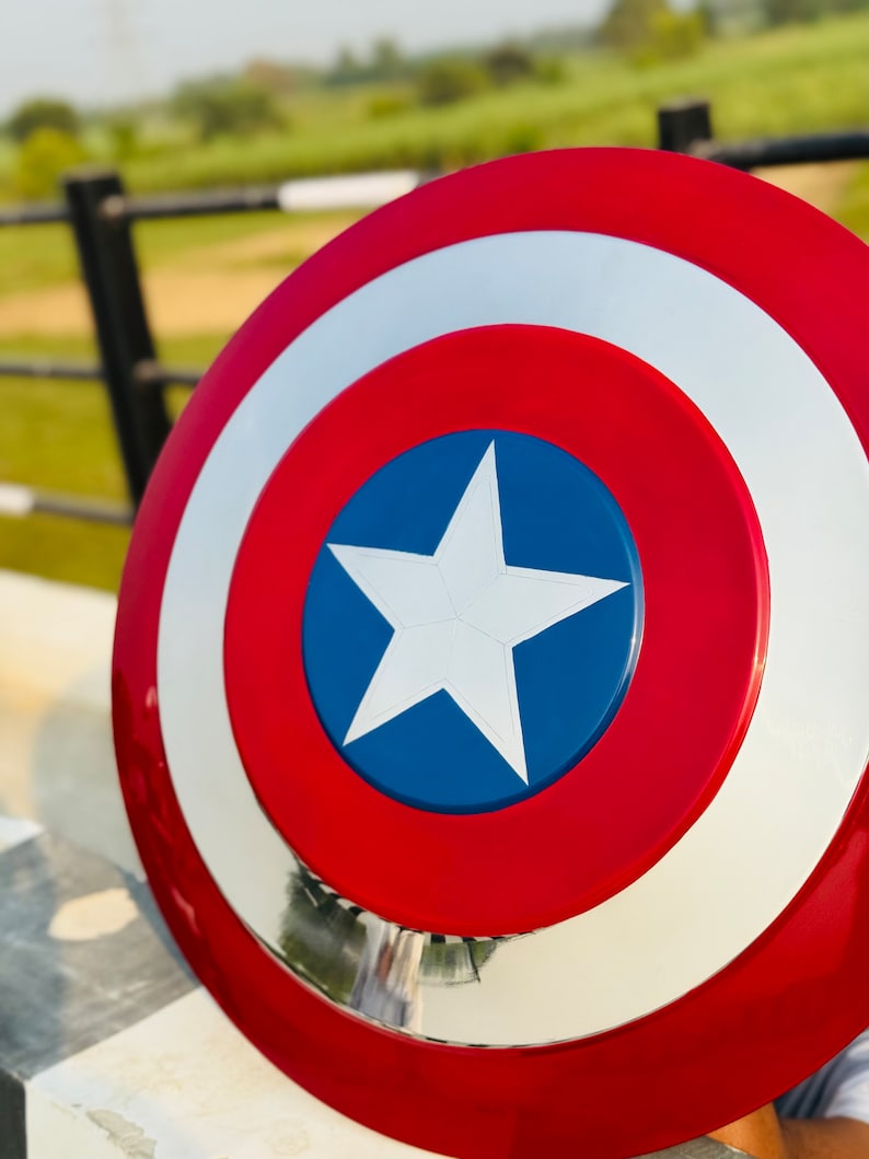 May include: A red, white, and blue Captain America shield with a white star on a blue circle. The shield is made of metal and has a shiny finish.
