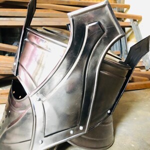 K&ouml;nnte beinhalten: Ein silberner Helm mit einer spitzen Spitze und einer Gesichtsmaske. Der Helm hat einen Lederriemen an der Unterseite.