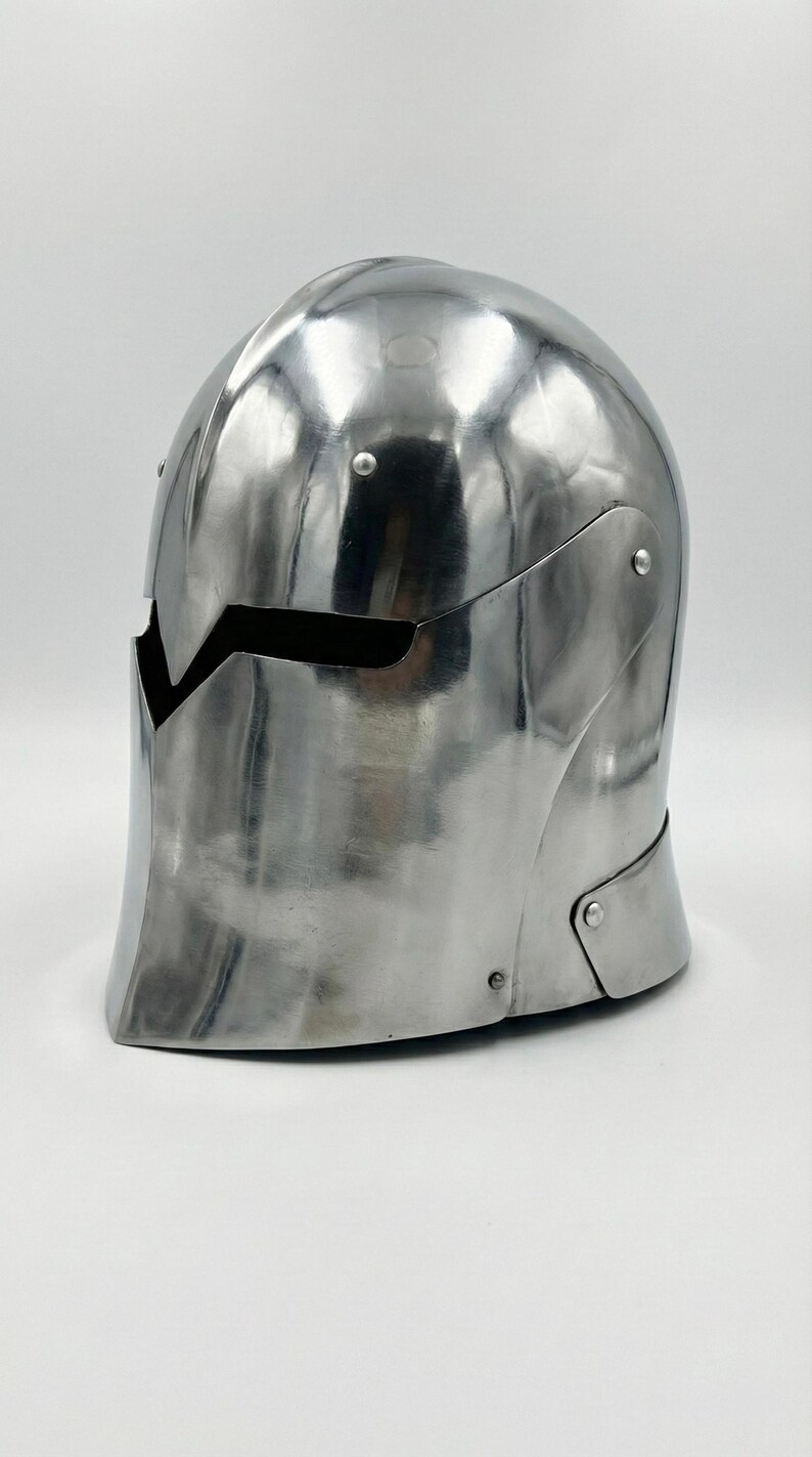 Puede incluir: Un casco medieval pulido de color plateado, con una parte superior redondeada y una abertura para la visera. El casco est&aacute; hecho de metal y tiene una superficie lisa y reflectante. Est&aacute; dise&ntilde;ado para proteger la cabeza y la cara.