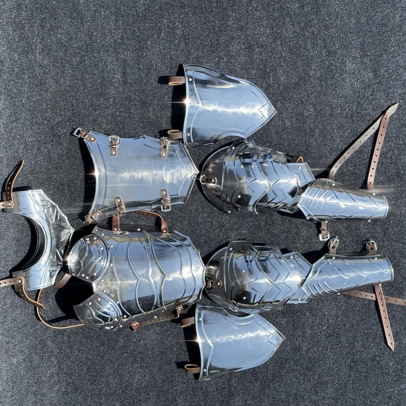 K&ouml;nnte beinhalten: Ein Satz polierter Silberr&uuml;stung, bestehend aus Brustpanzer, Schulterplatten und Armschienen. Die R&uuml;stung ist aus Metall und hat eine gl&auml;nzende Oberfl&auml;che.