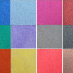 May include: A collection of 12 small squares of coloured sand. The colours are blue, light blue, pink, red, green, purple, grey, dark grey, orange, yellow, coral, and brown.