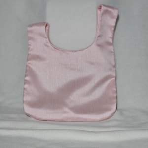 May include: A light pink satin tote bag with a rounded bottom and a single handle. The bag is made of a smooth, shiny fabric and is displayed against a white background.