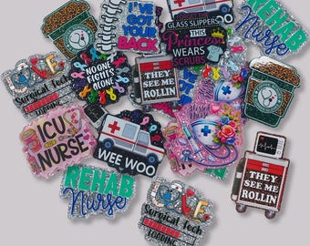 May include: A collection of glittery, colorful pins with medical and nursing themes. Designs include coffee cups, ambulances, medical symbols, and phrases like "ICU Nurse," "Rehab Nurse," and "They See Me Rollin."