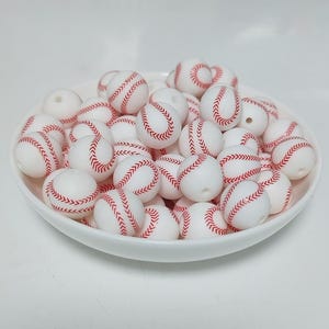 May include: A bowl filled with white silicone beads with red baseball stitching.