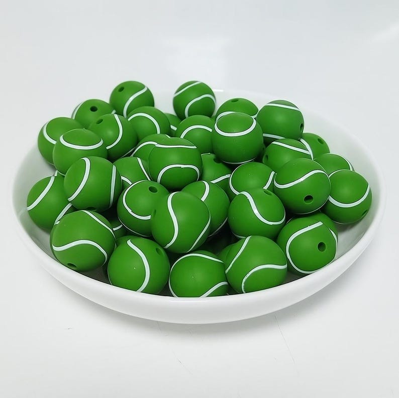 May include: A bowl filled with green and white silicone beads shaped like tennis balls.